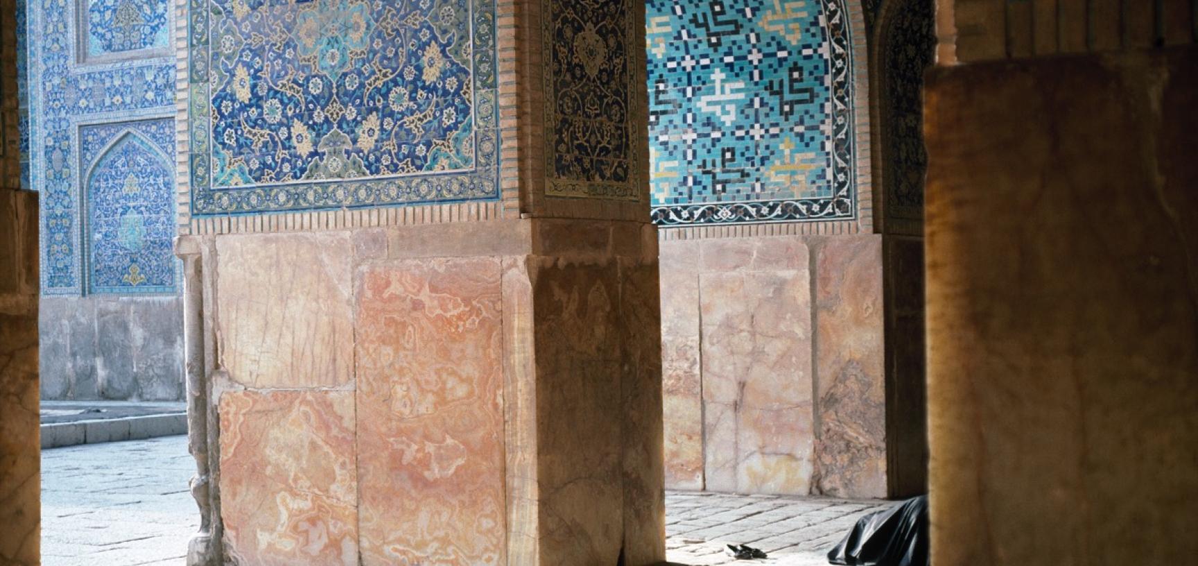 A person prays behind a pillar