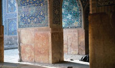 A person prays behind a pillar