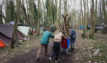 Men carrying wood on a trolley.